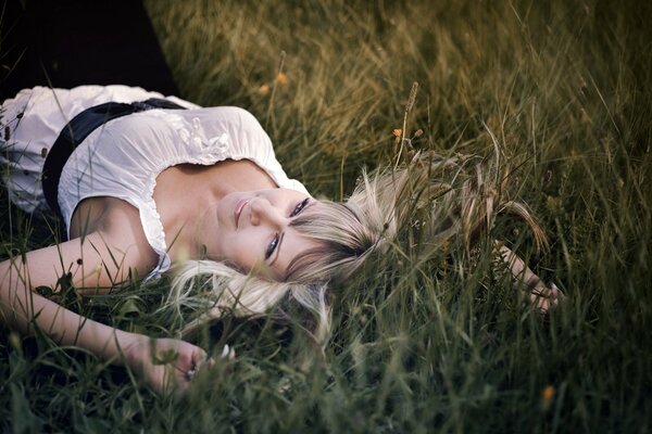 The girl is lying in the green grass