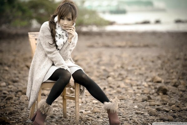 Ragazza in autunno in riva al mare su una sedia