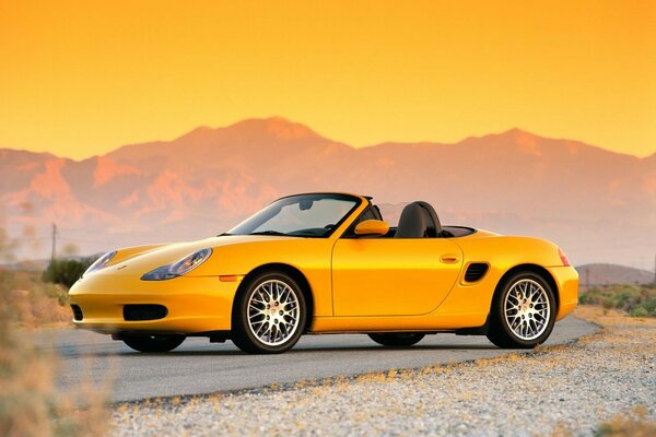 Yellow Porsche on the background of mountain ranges