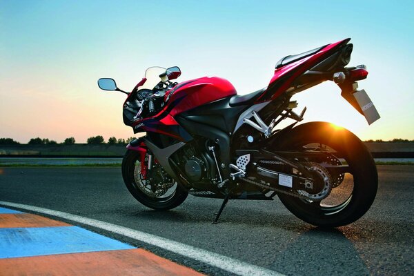 A red sports motorbike in the shade of the sun