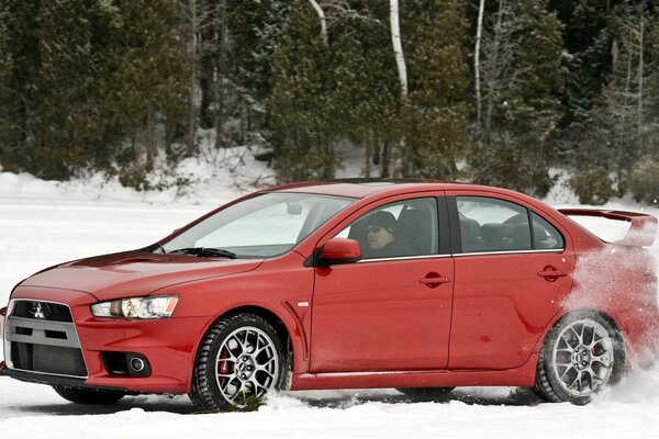 El rojo mucibisi Lancer entra en un giro en la pista de invierno