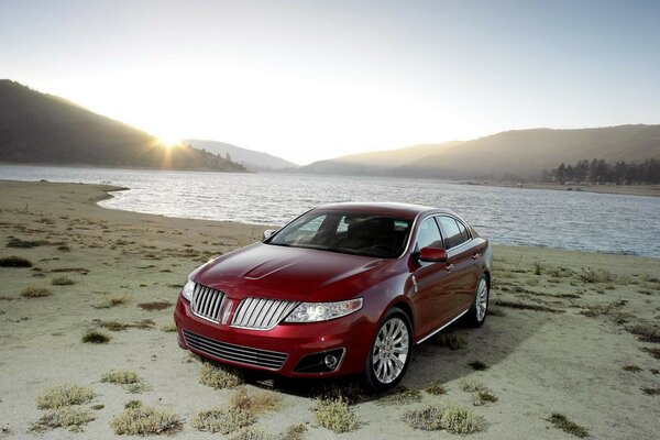 Voiture rouge se trouve sur la plage de sable