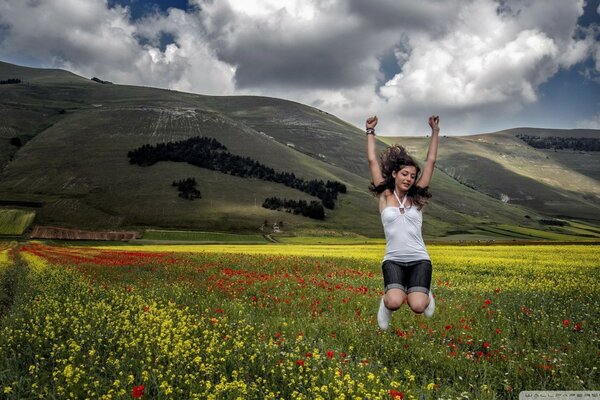 Chica en un salto en el fondo de las montañas