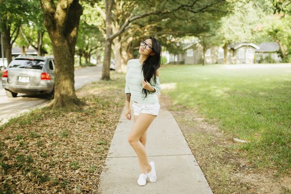 Asian woman with glasses is standing in the park