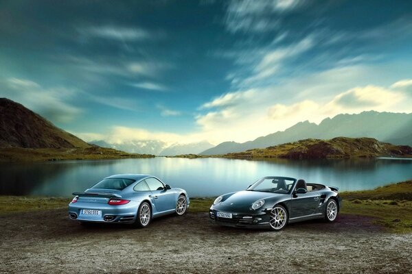 Two expensive cars are parked on the beautiful shore of the lake