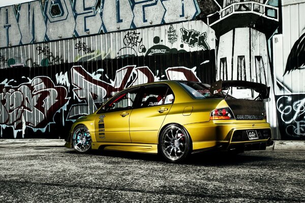 Yellow Mitsubishi on the background of a wall with graffiti
