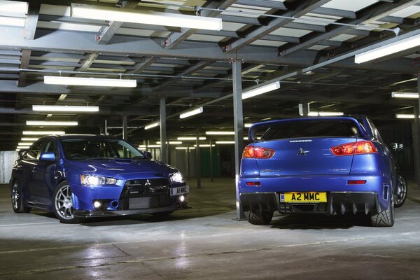 Two blue Mitsubishi in a covered parking lot