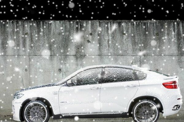 Белый BMW X6 под падающим снегом