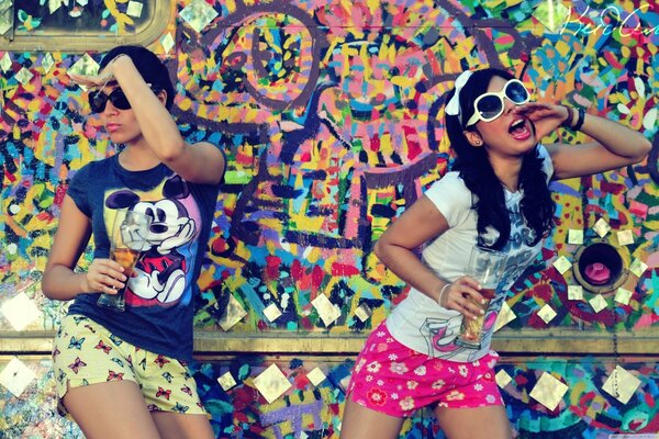 Young girls posing under graffiti