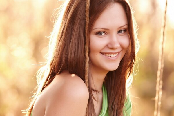 A girl with red hair smiles on a swing