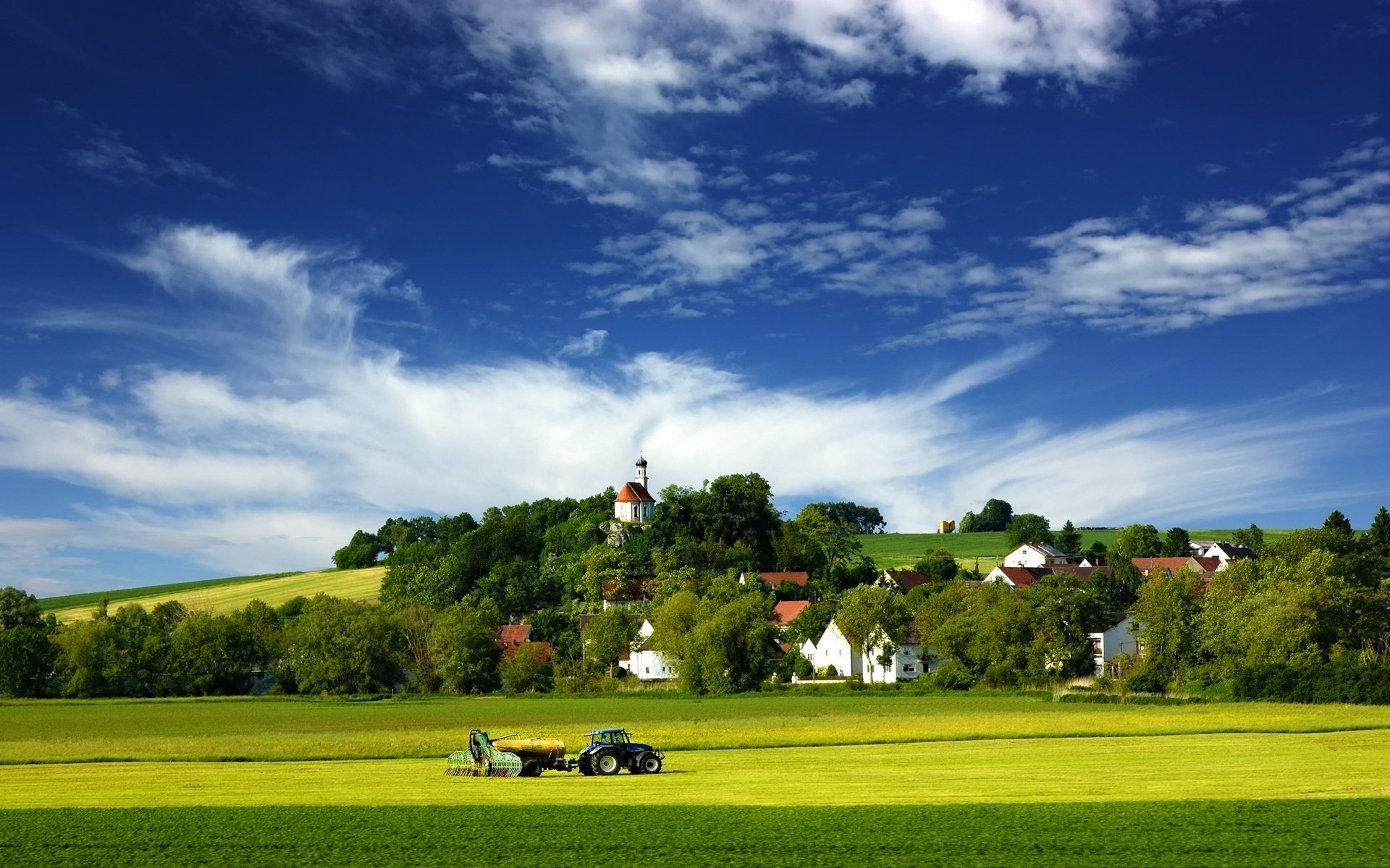 heuhaufen sommer traktor feld wiese grün natur himmel wolken landschaft dorf häuser bäume hügel