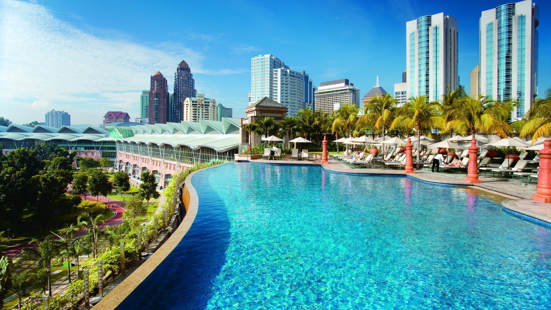 kuala lumpur fleurs malaisie hôtel piscine eau turquoise palmiers bâtiments maisons ville loisirs ciel gratte-ciel journée journée ensoleillée végétation verdure parasols chaises longues arbres