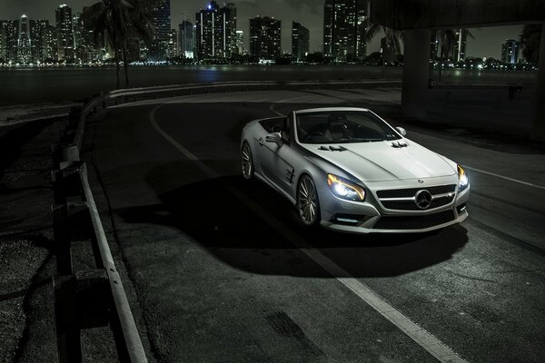 La ciudad de la noche y el coche de Mercedes en un fondo gris