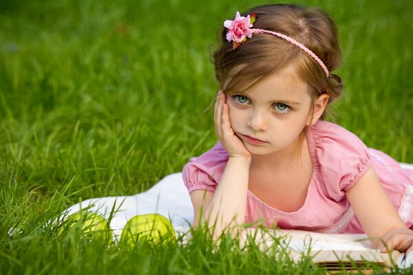 Enfant sur la pelouse avec un livre et des pommes en méditation