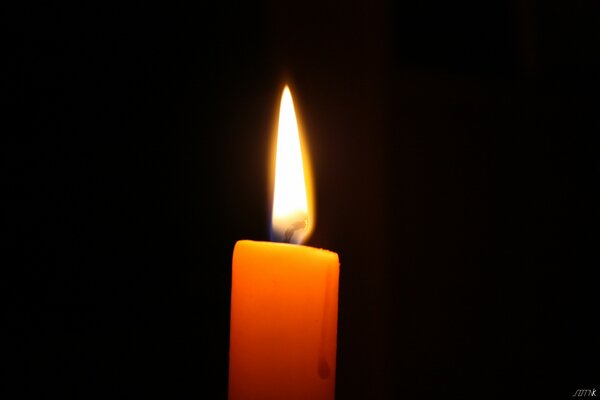 A candle burning in complete darkness