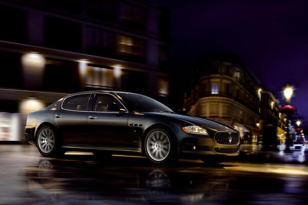 Coche negro Maserati en el fondo de la ciudad de la noche