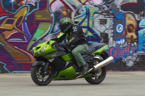 Un hombre en una moto contra un grafiti en una pared