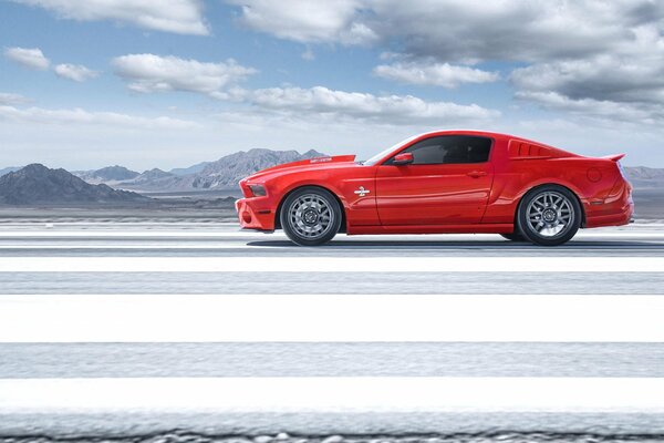 A red Ford Mustang rides under the clouds