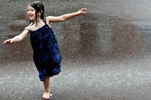 Bambina che balla sotto la pioggia estiva