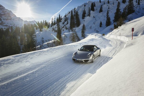 Silver car on a snowy road in the mountains