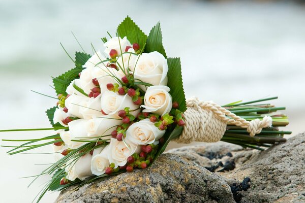 Brautstrauß aus weißen Rosen auf Steinen