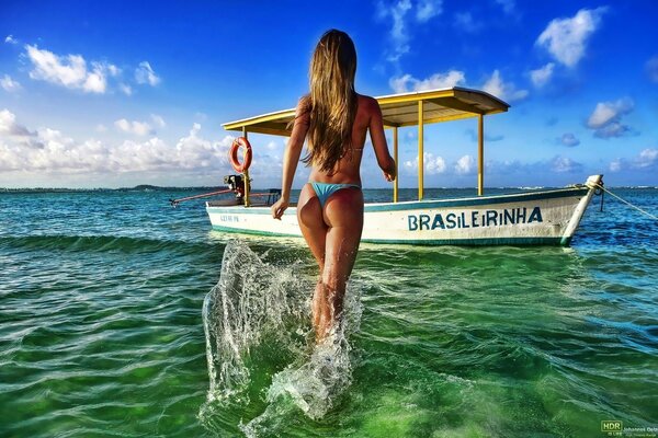 Chica en bikini caminando hacia el barco