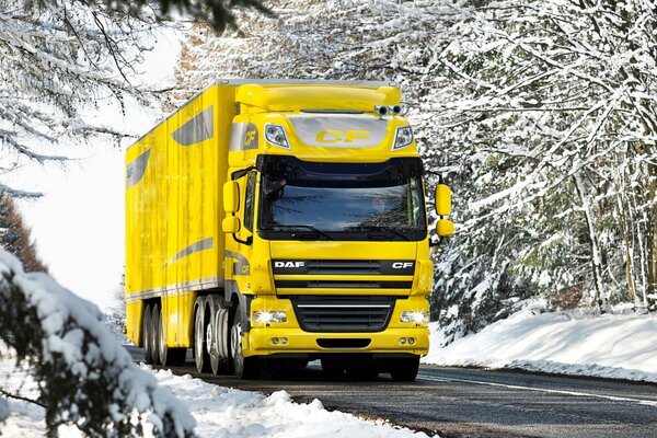 En invierno, un camión amarillo conduce por una carretera cubierta de nieve