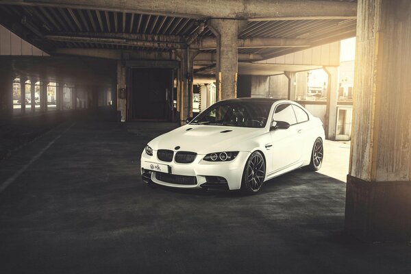 A white BMW stands among gray columns