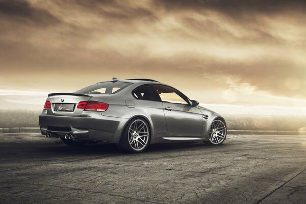 Silver BMW automobile on a gray road under a brown sky