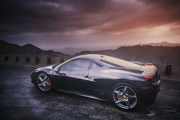 Ferrari noir en profil sur fond de montagnes