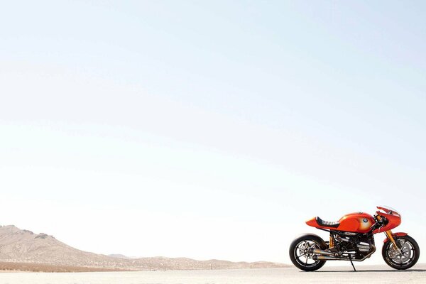 Orange motorcycle on the background of the sky and mountains