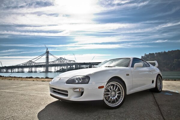 Against the background of the sky, the bridge and the river - a white Toyota sports car