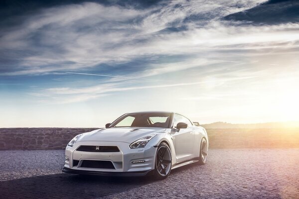 Nissan blanco contra el cielo diurno a la luz del sol