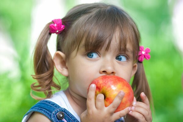 A girl with blue eyes eats an apple