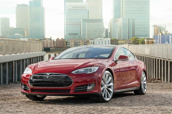 Red Tesla on the background of city buildings