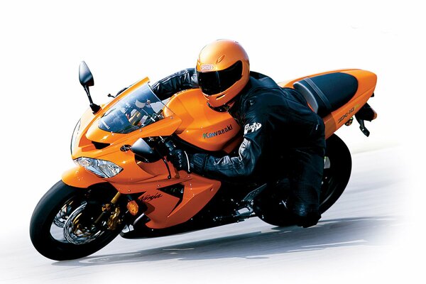 Пилот в шлеме на оранжевом мотоцикле kawasaki zx-10r