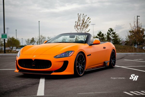 Voiture orange marque Maserati classe convertible vue de face latérale
