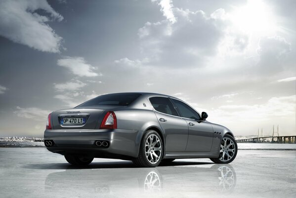 A silver Maserati car under a sunny sky in gray tones