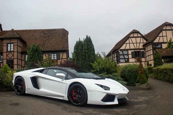 A white lamborghini parked next to the houses