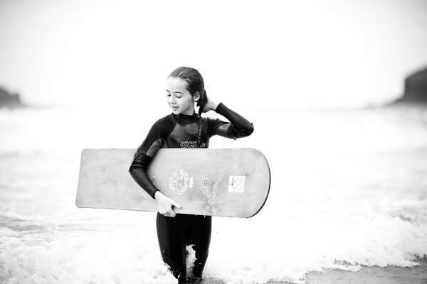 Black and white photo of a girl with a surfboard in her hands