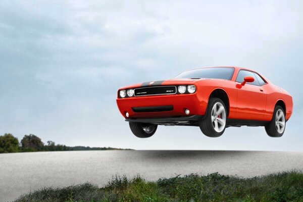 Der orange challenger srt8 liegt mit hoher Geschwindigkeit in der Luft