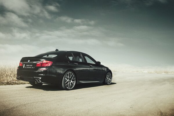 Negro BMW M5 en la carretera de arena