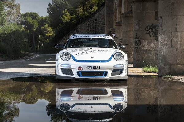 Une Porsche blanche se reflète dans un miroir d eau lisse