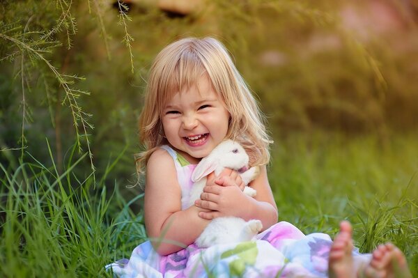 Fille joyeuse avec un lapin blanc assis sur l herbe et rire