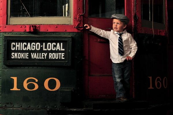 A little gentleman boy is standing by the train