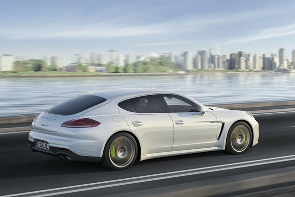 Un Porsche panamero blanco recorre el asfalto en medio de la ciudad