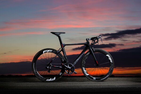 Bicicletta in carbonio nero su sfondo tramonto