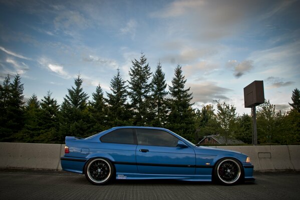 Niebieskie tuningowane BMW E36 na tle lasu