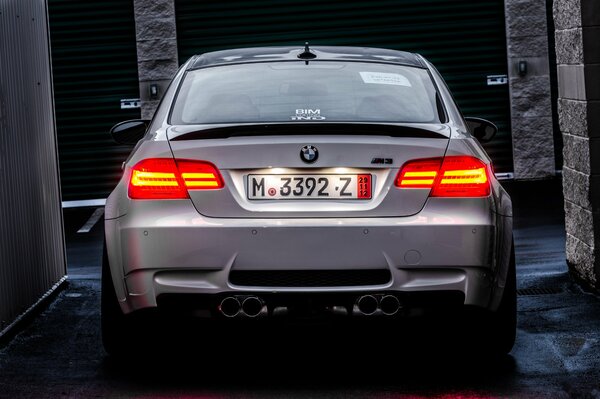 A white BMW with red headlights is standing on the street