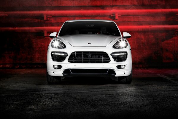 White Porsche Cayenne in the dark with red backlight on the background of no pipes